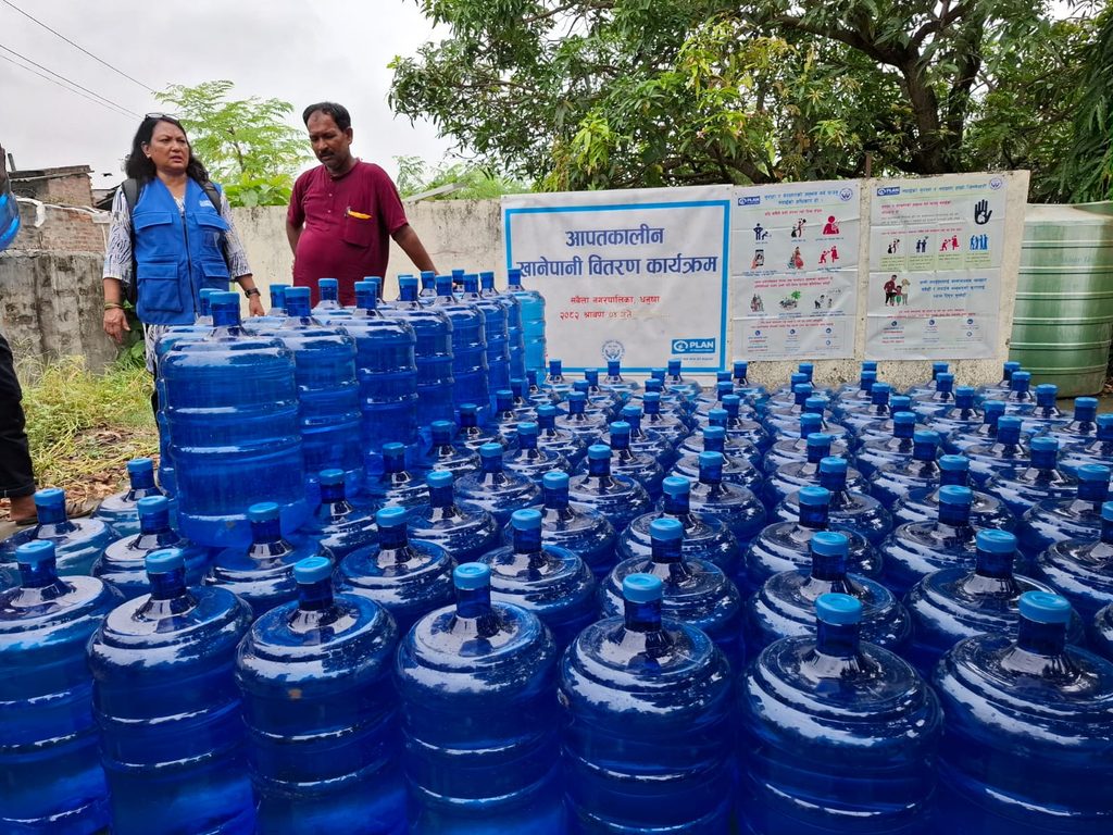 Plan staff standing in front of water jars getting ready for the distribution in Janakpur.