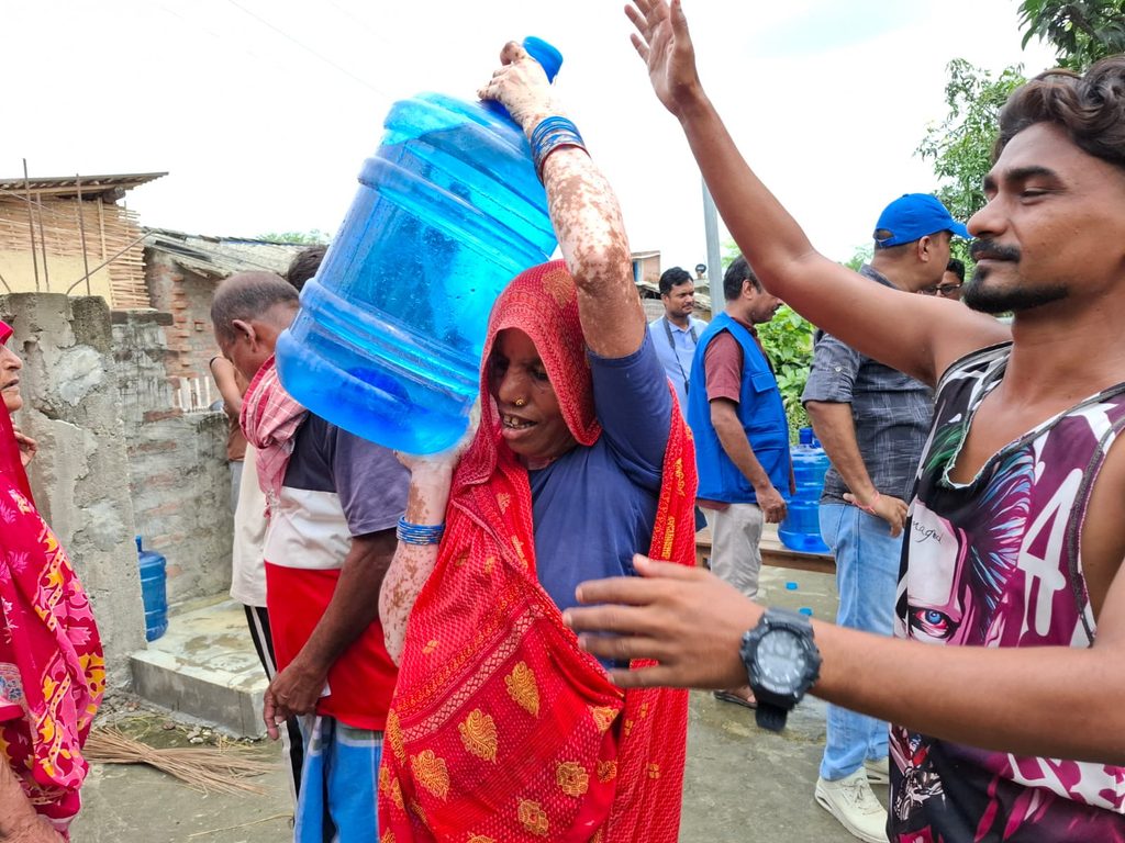 A man helps a woman carrying clean drinking water.