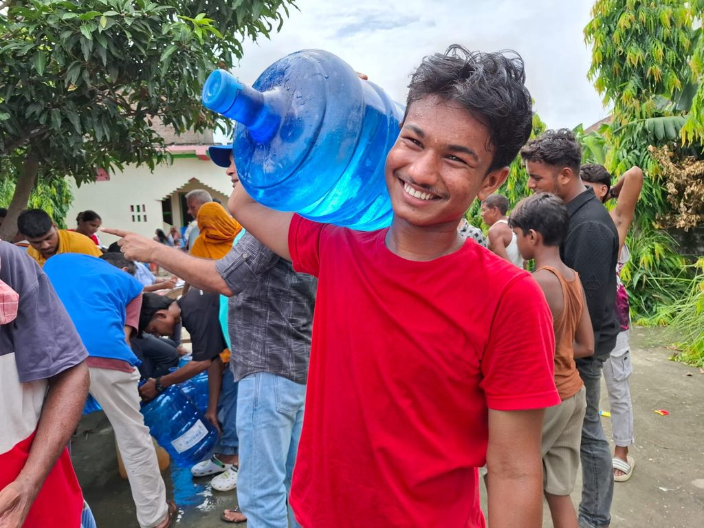 A boy with smile carrying the clean drinking water jar on his shoulder.