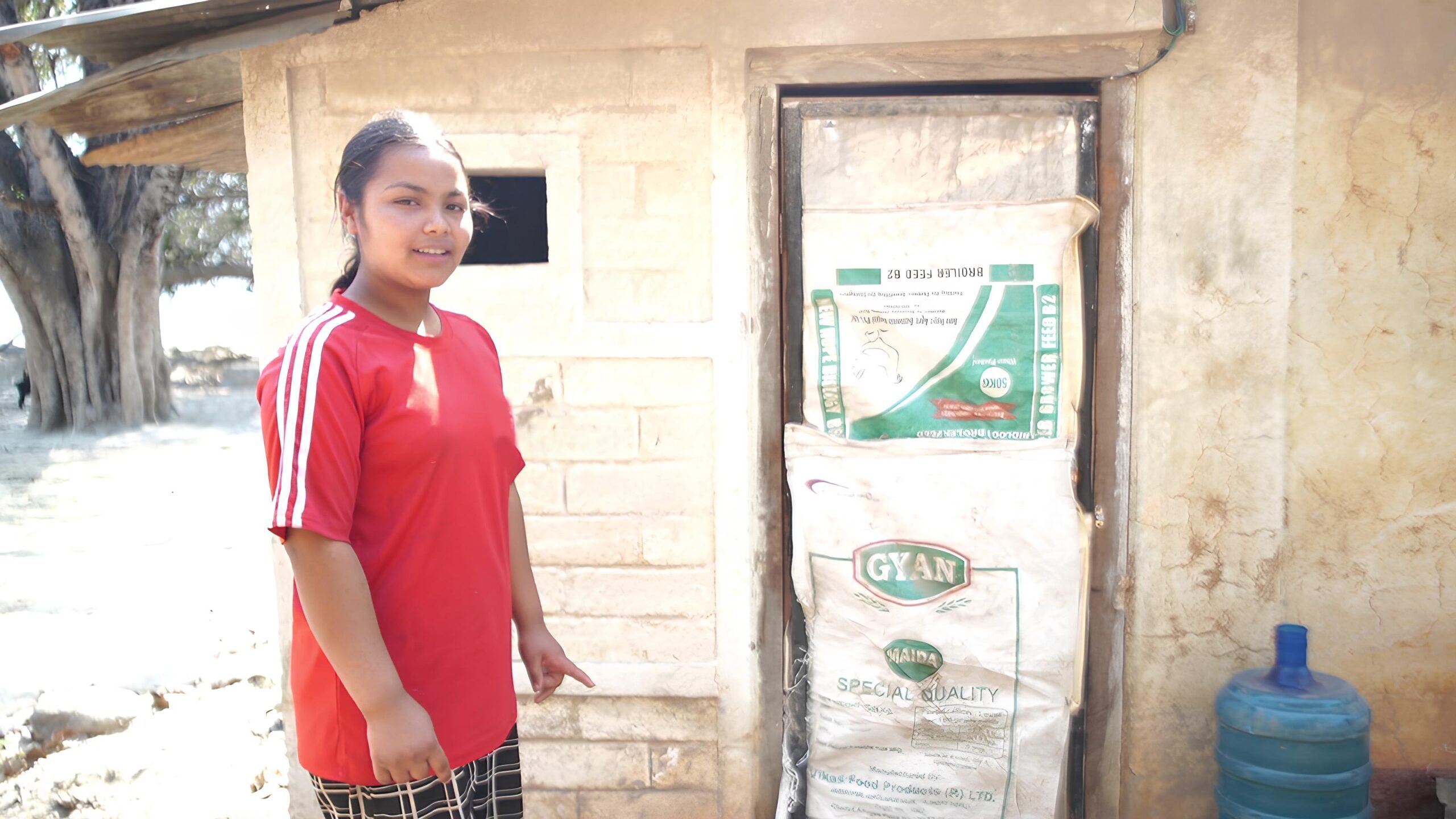 A girl wearing red t-shirt showing the temporary toilet.