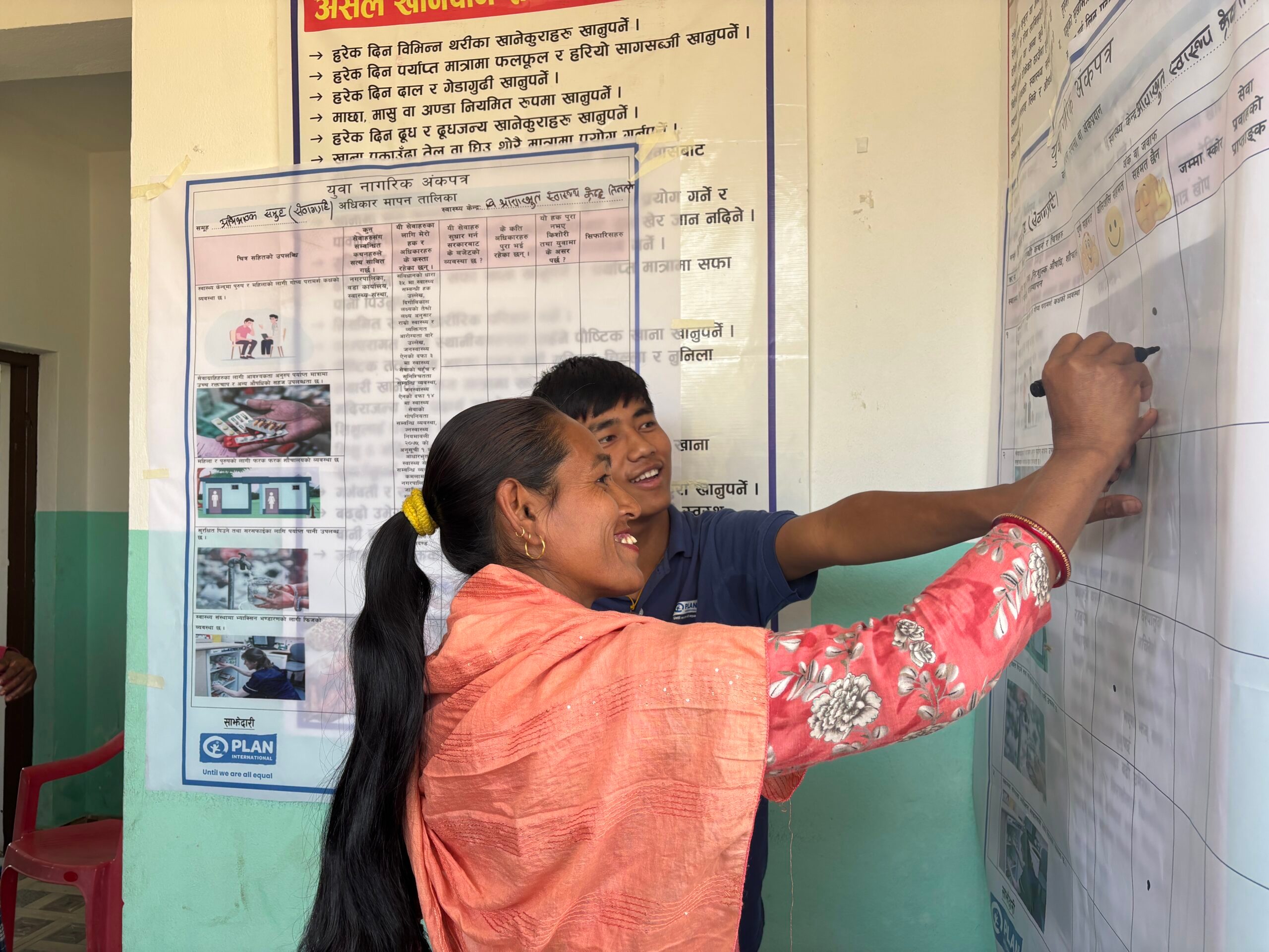A youth volunteer and a community member writing on a board.