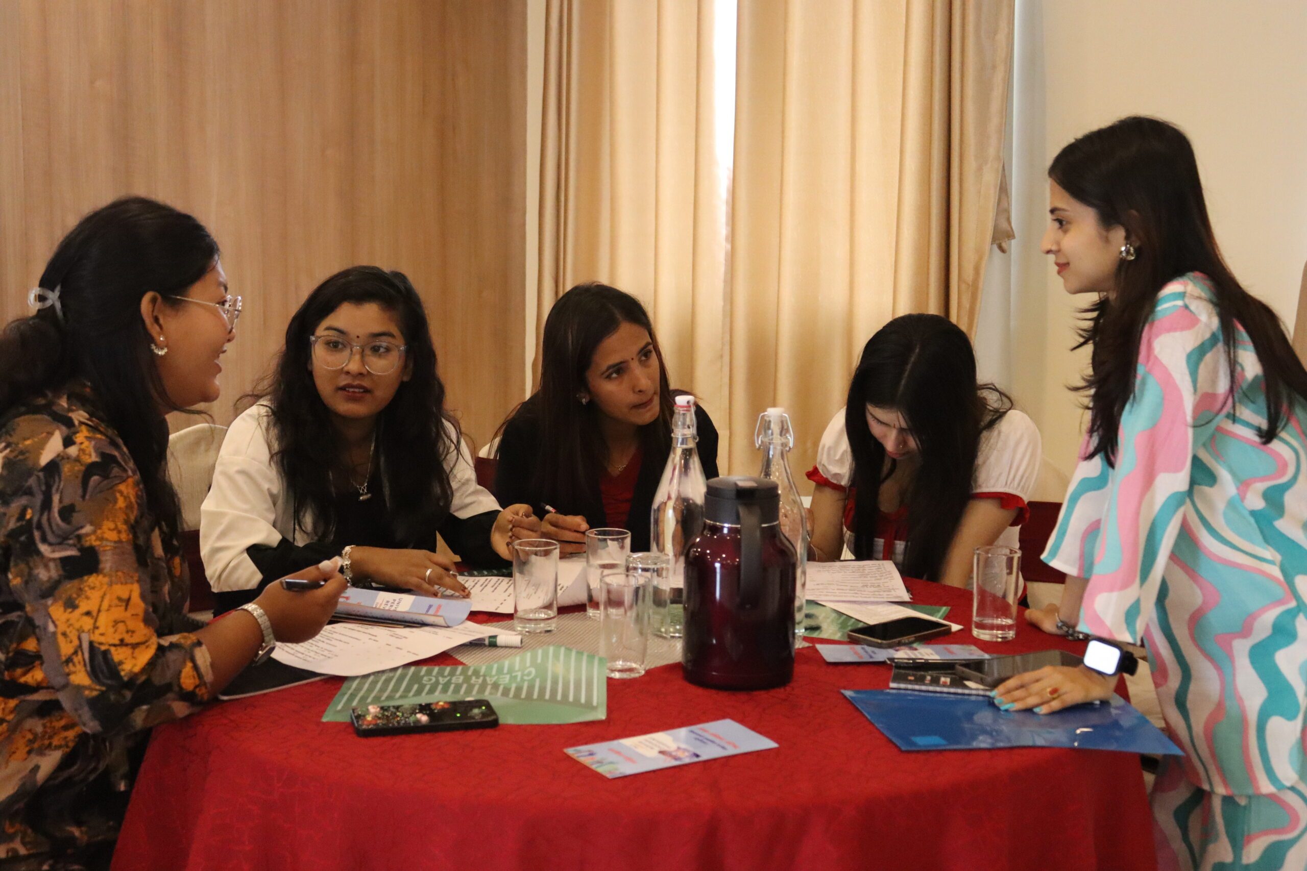 Five young women in sitting around and discussing during UPR workshop.