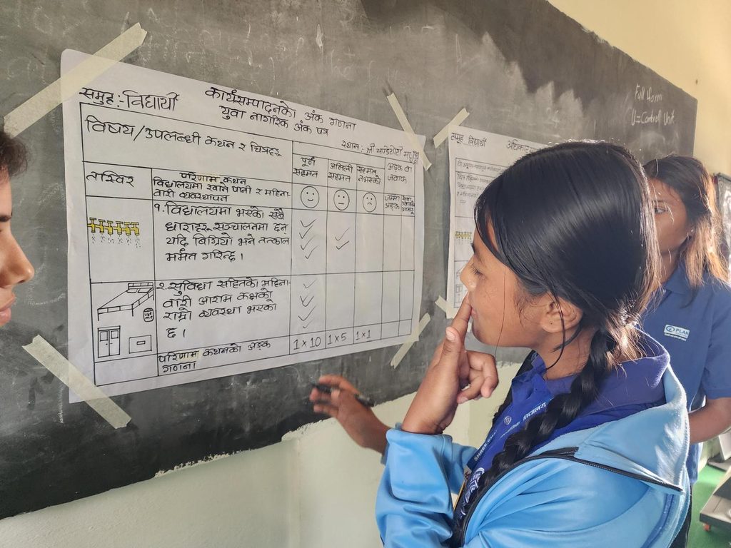 A girl looking at the chart paper on the black board and thinking