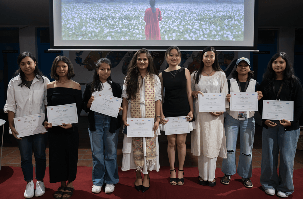 Eight young filmmakers standing in front of the screen and holding certificates