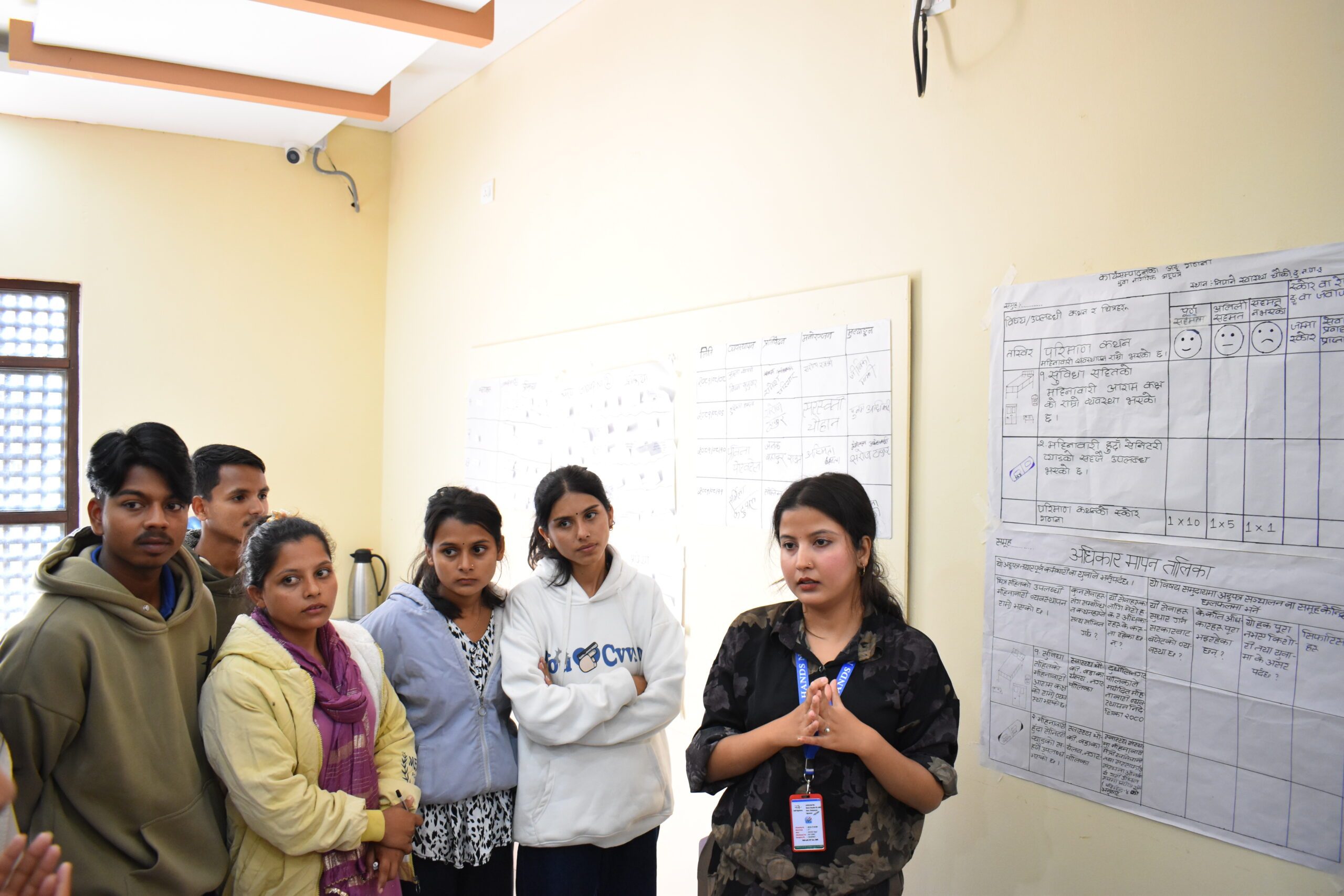 A group of young people standing and listening to the facilitator in a training.