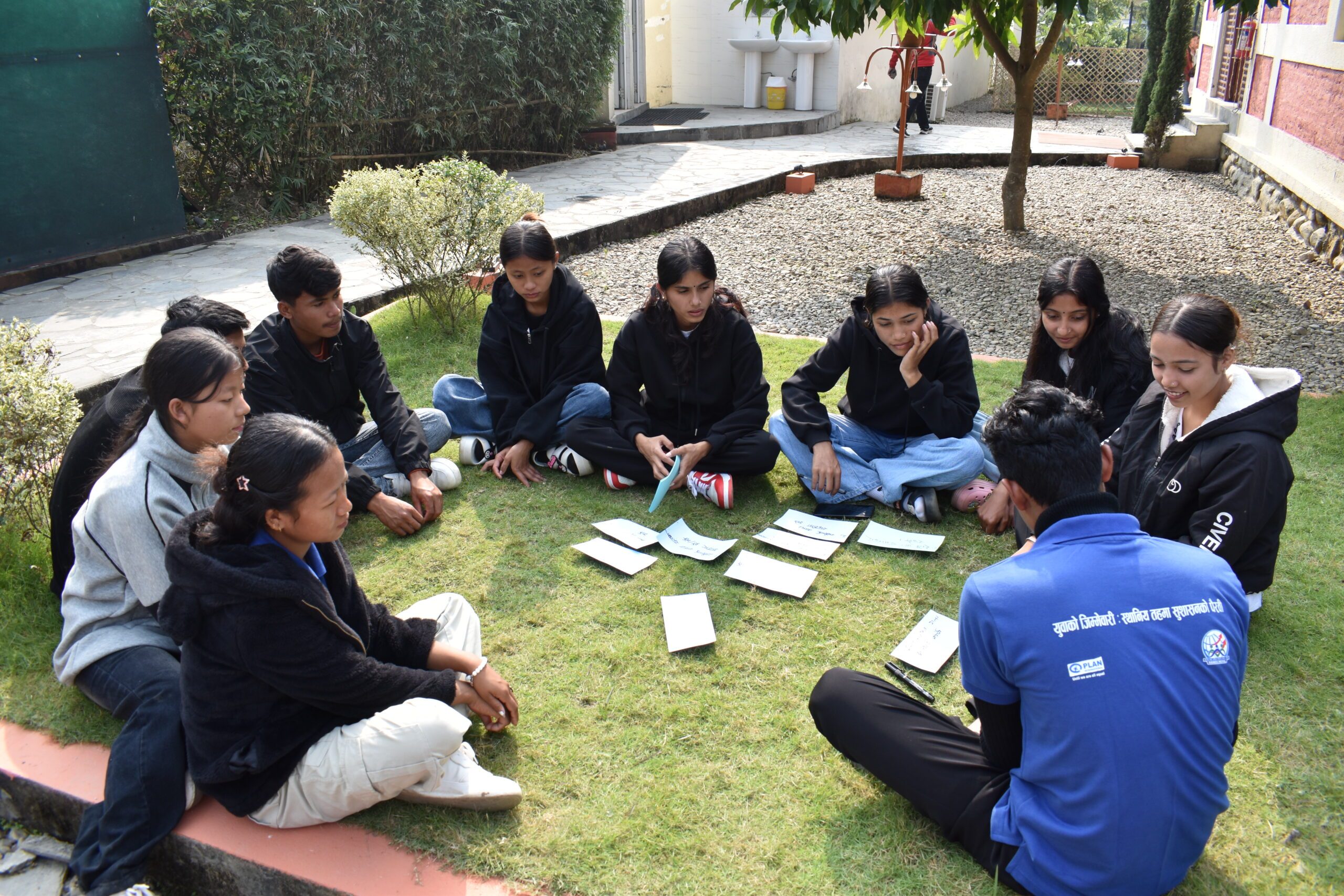 Youth volunteers sitting in a circle in a garden during training