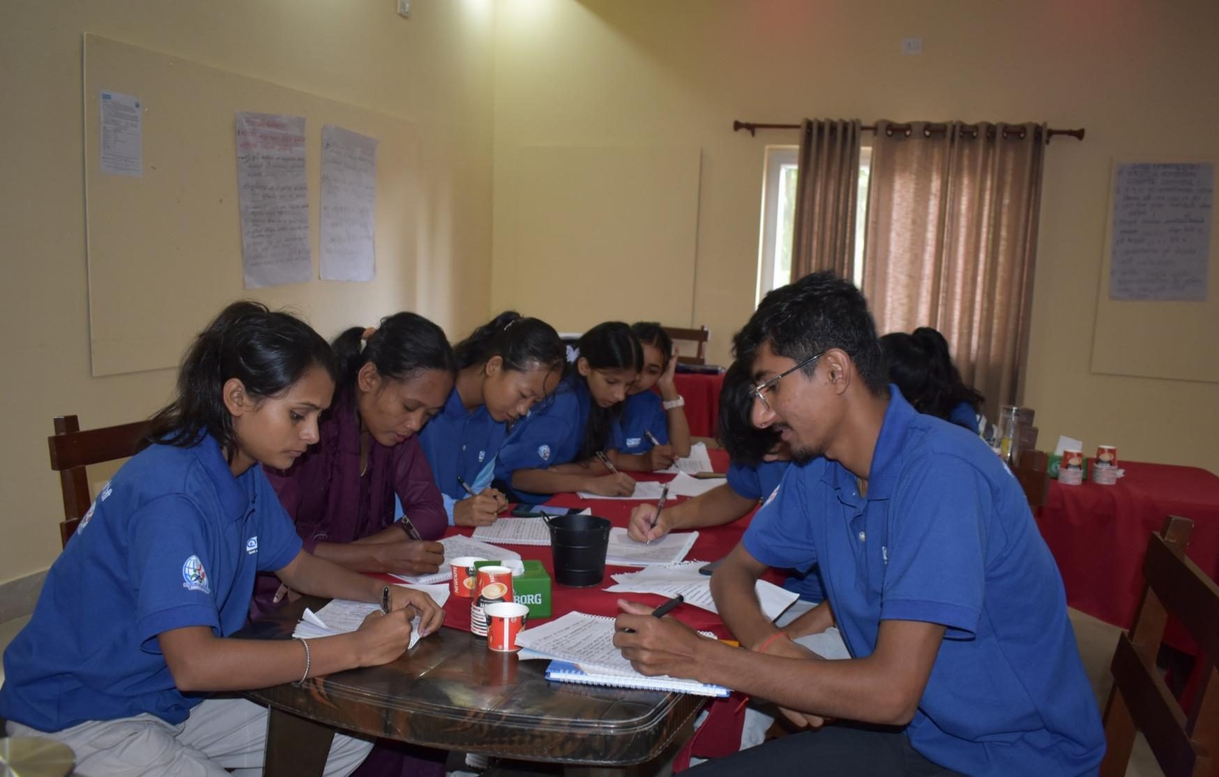 A group of youth volunteer wearing blue t-shirt are filling pre-test questionnaire during the training.