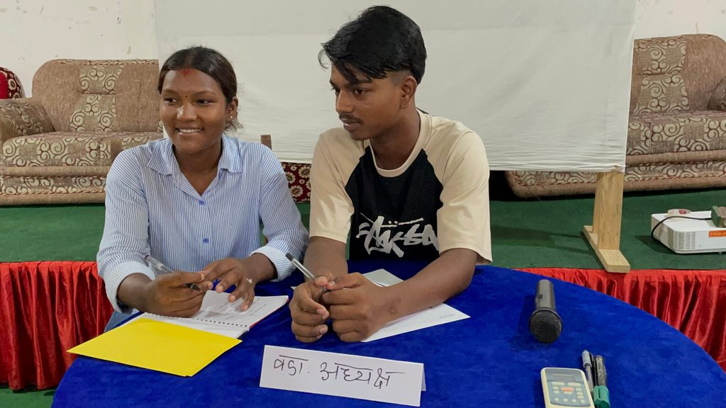 A boy and a girl sitting together and attending training.