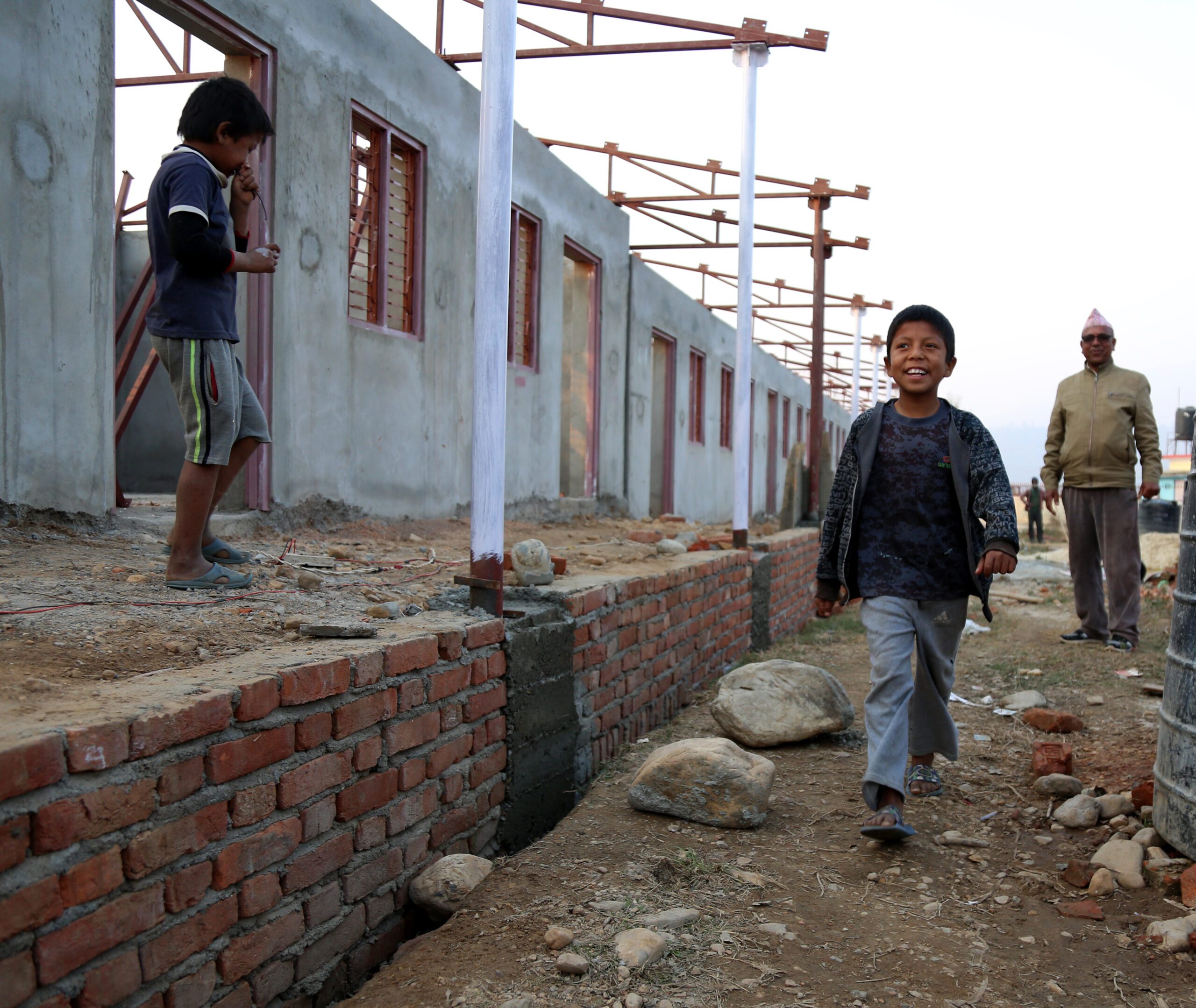 A school building under construction, a child is happy walking.