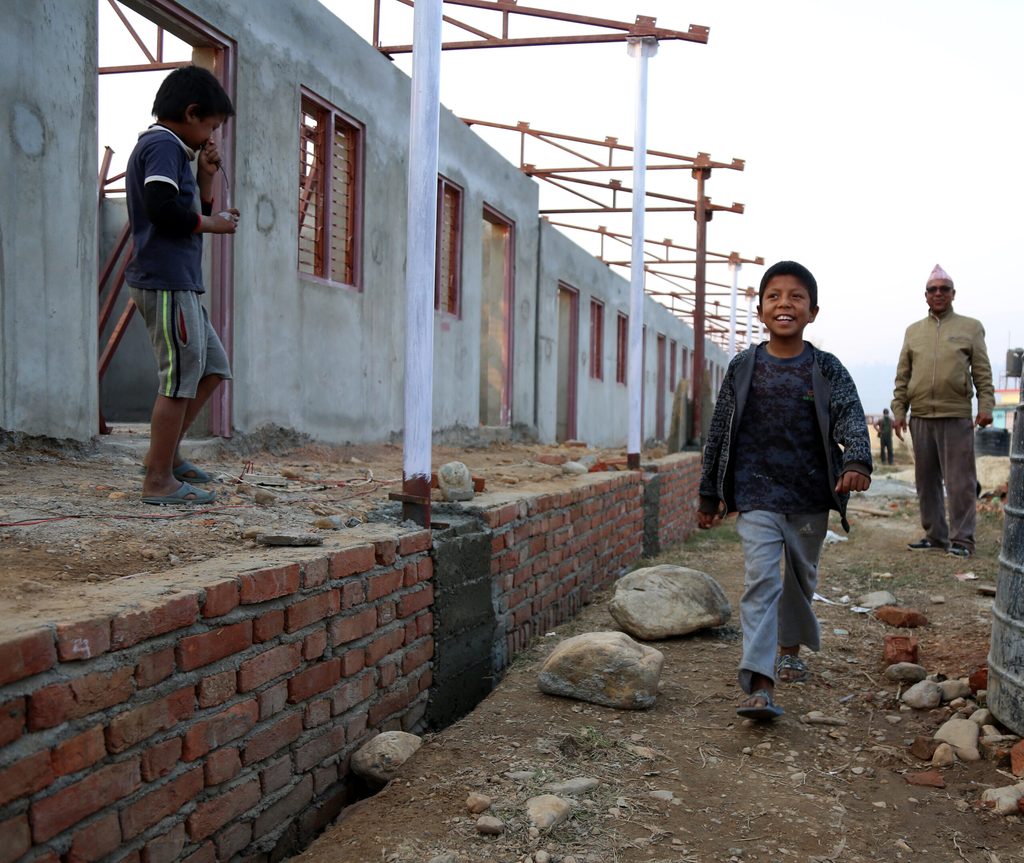 A school building under construction, a child is happy walking.