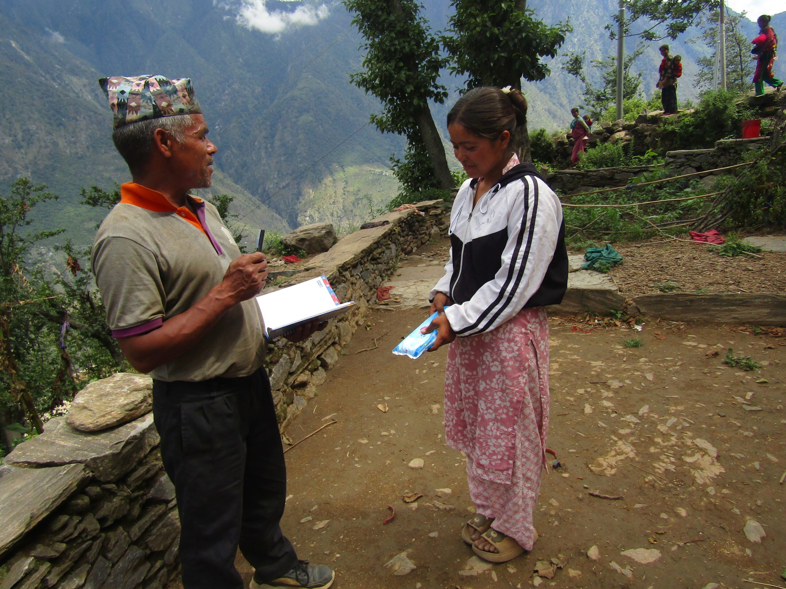 A father in front of their house giving sanitary pads to his daughter. 