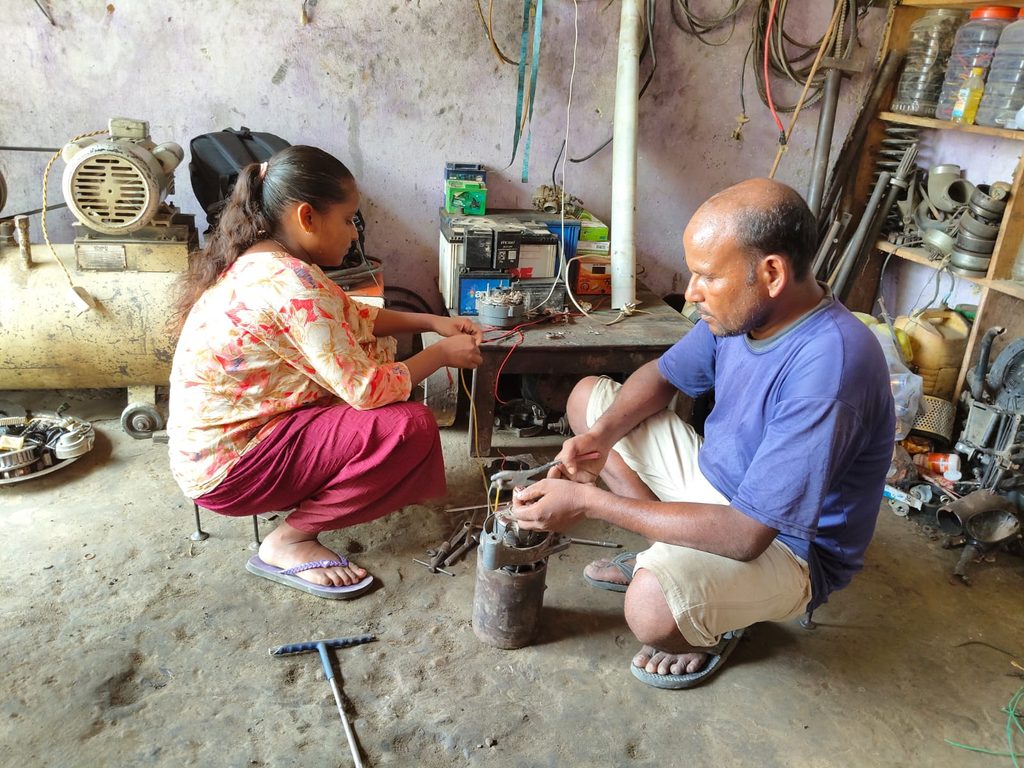 Anchal on left sitting with her father Narendra in right and helping him in his garage.
