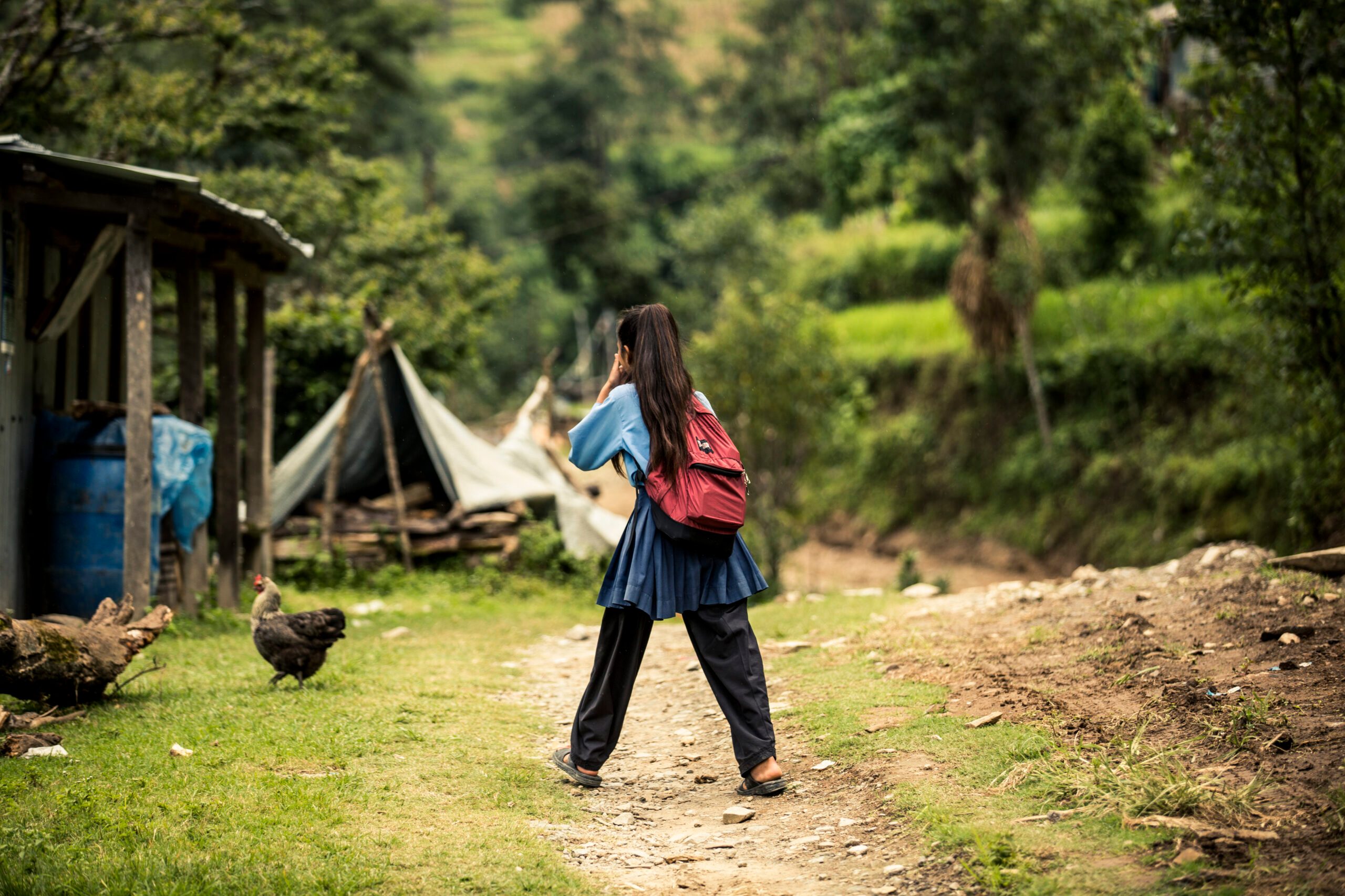 A girl in school uniform walking towards temporary classroom.