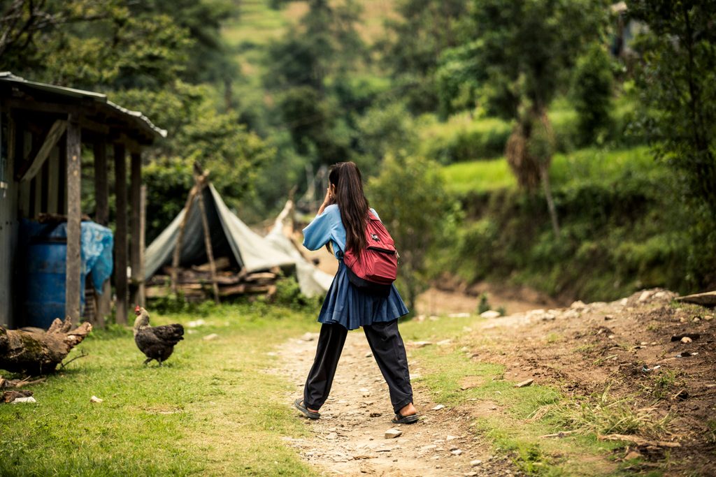 A girl in school uniform walking towards temporary classroom.