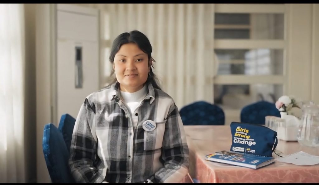 A young activist, deaf, Rabita sitting on a chair, Plan's notebook and pouch beside her.