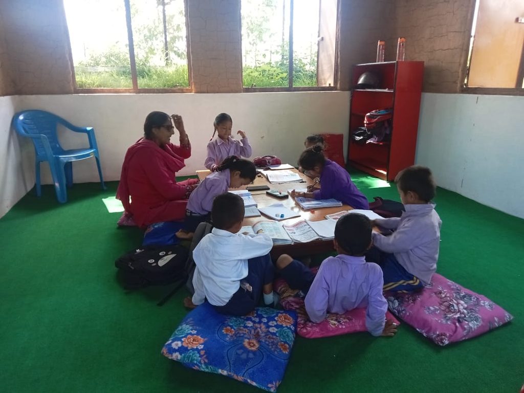 Children doing their classroom activity with their teacher in their new classroom.