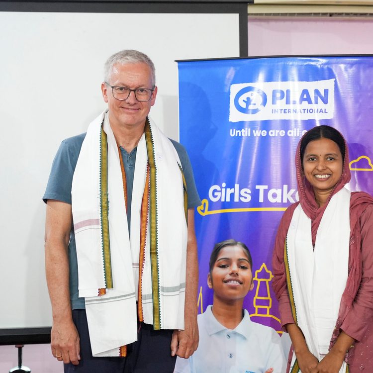 Sana wearing Kurta with while shawl on right and Frank on left standing and posing for camera.