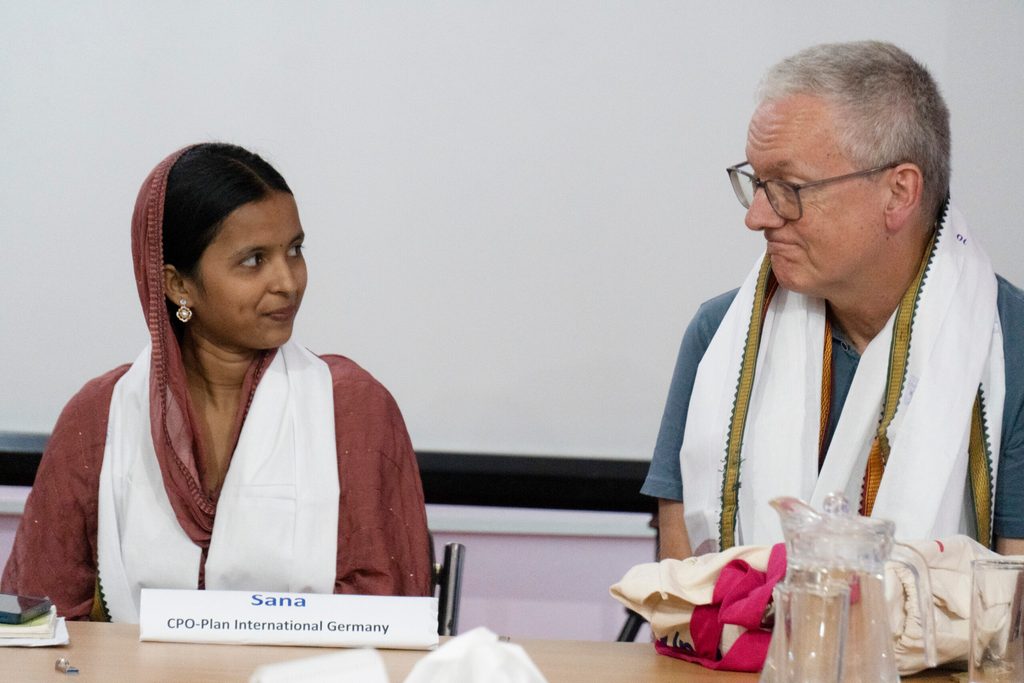 Sana wearing white shawl (left) in conversation with Frank (left)