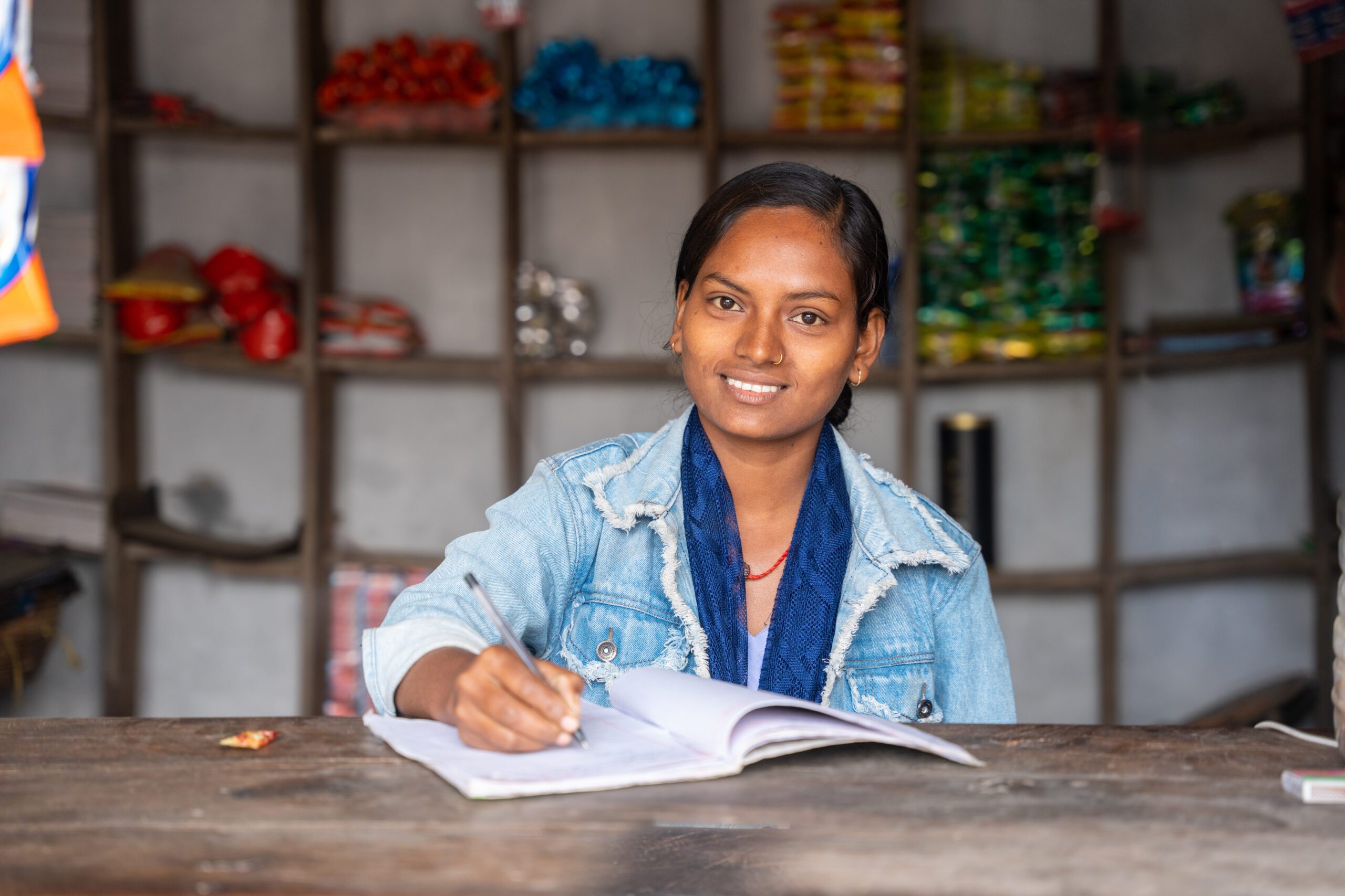 A young woman, Ashiya holding a pen and a note book in her shop.