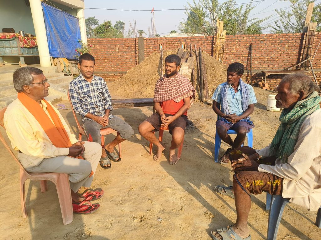 A group of men (5) sitting in chairs outsize and talking