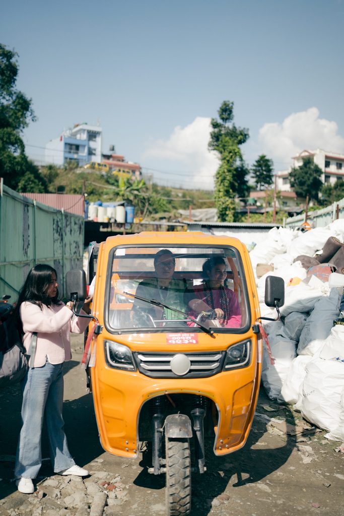 Aruna in pink sweat t-shirt siting in a yellow tempo with female driver