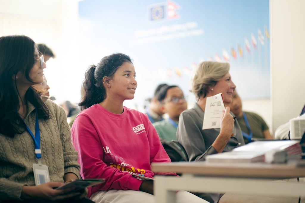 Aruna in the middle wearing pink sweat t-shirt and attending a meeting.