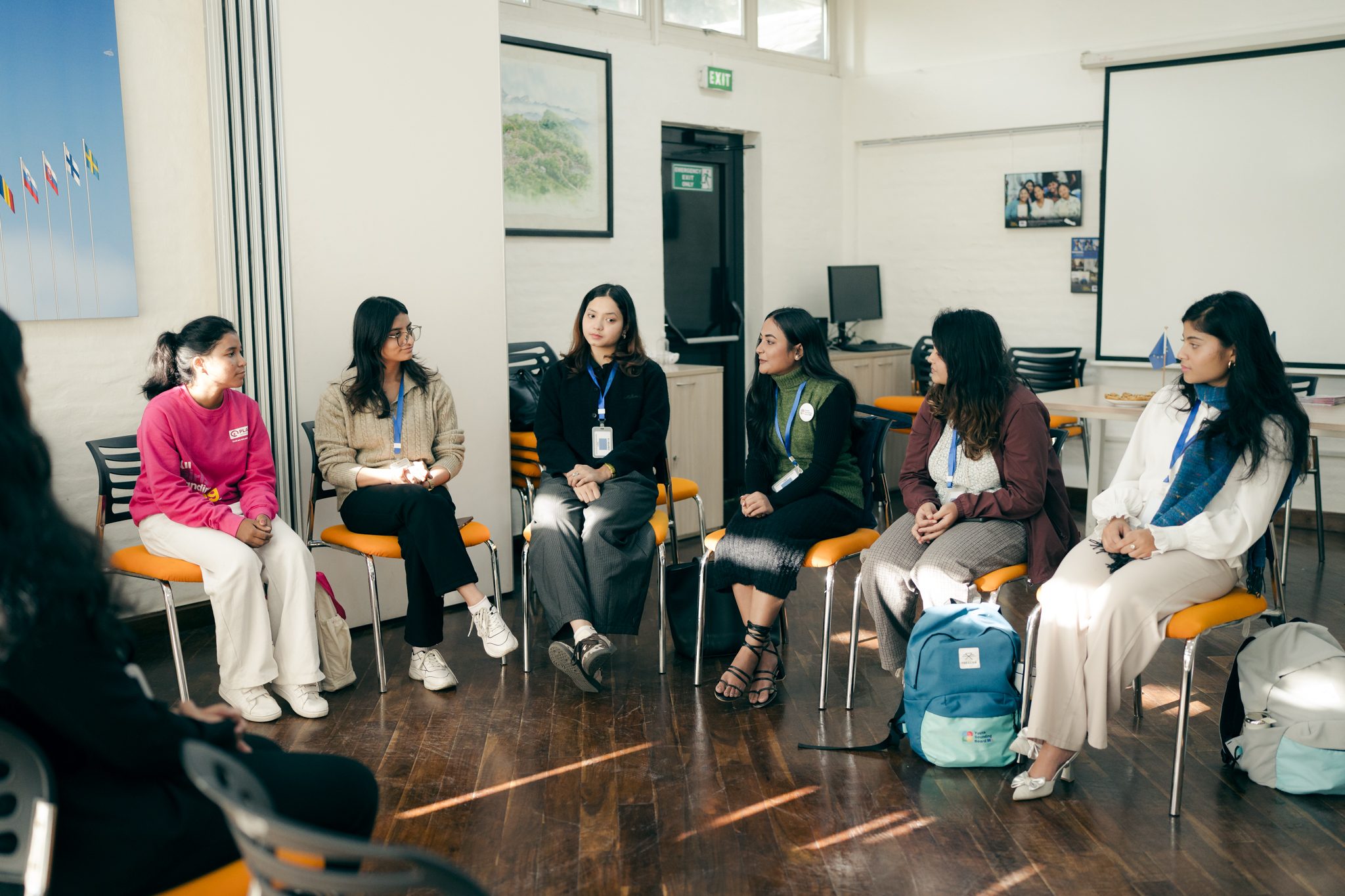 A group of young girls sitting on a chair and attending a meeting.