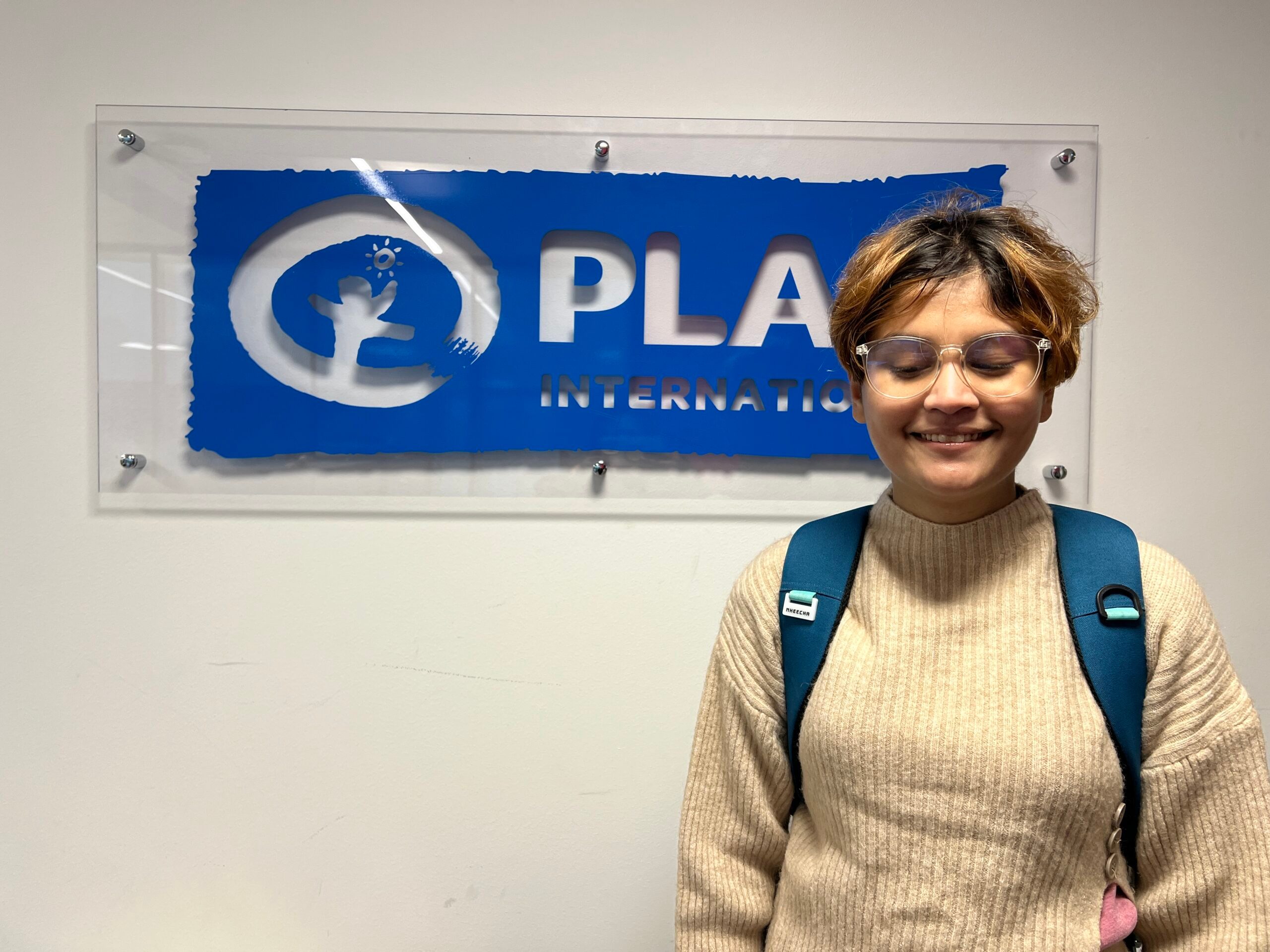 Smarika standing in front of Plan International logo in Finland. 
