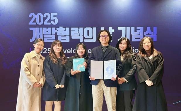 Six people standing and holding an award. Five female and 1 male. 