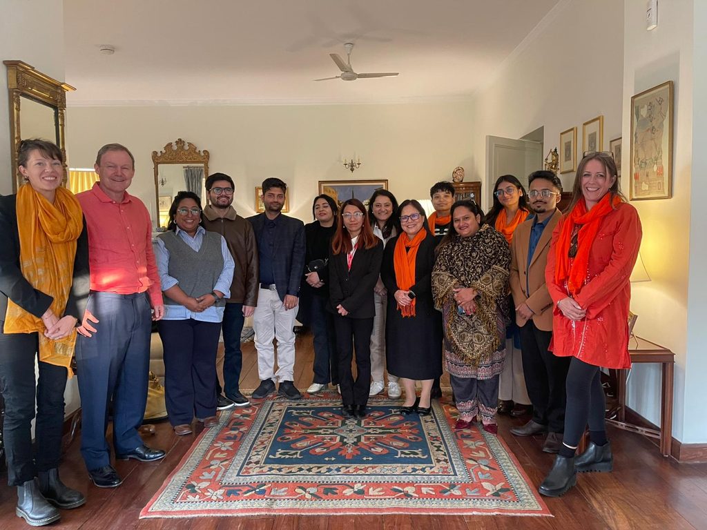 A group of youth from diverse background standing together with British Ambassador and Development Director at Ambassador's residence.