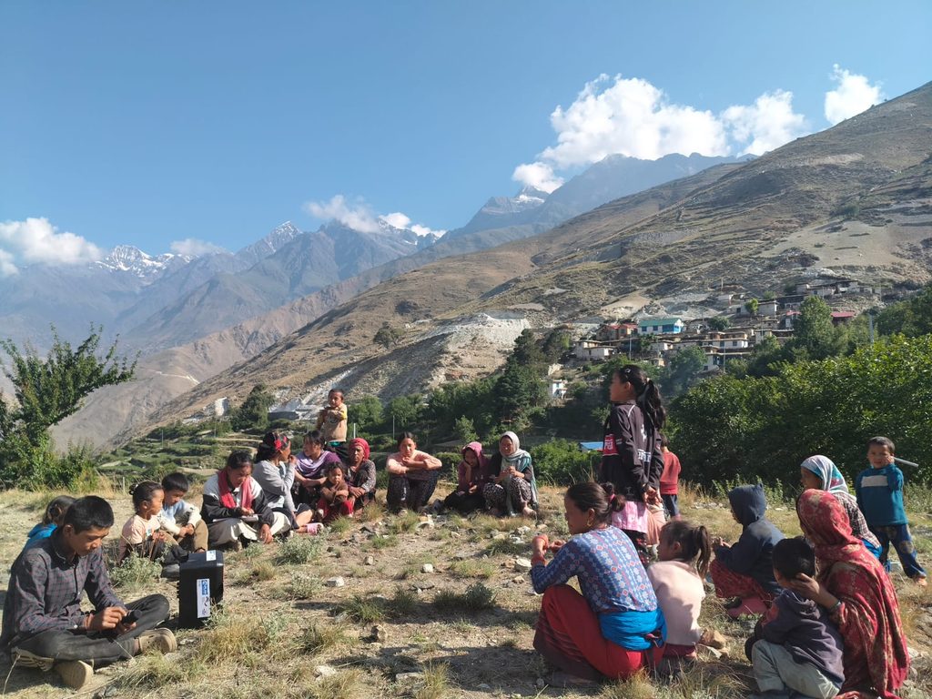 Sabitri standing in a group of people sitting in a circle