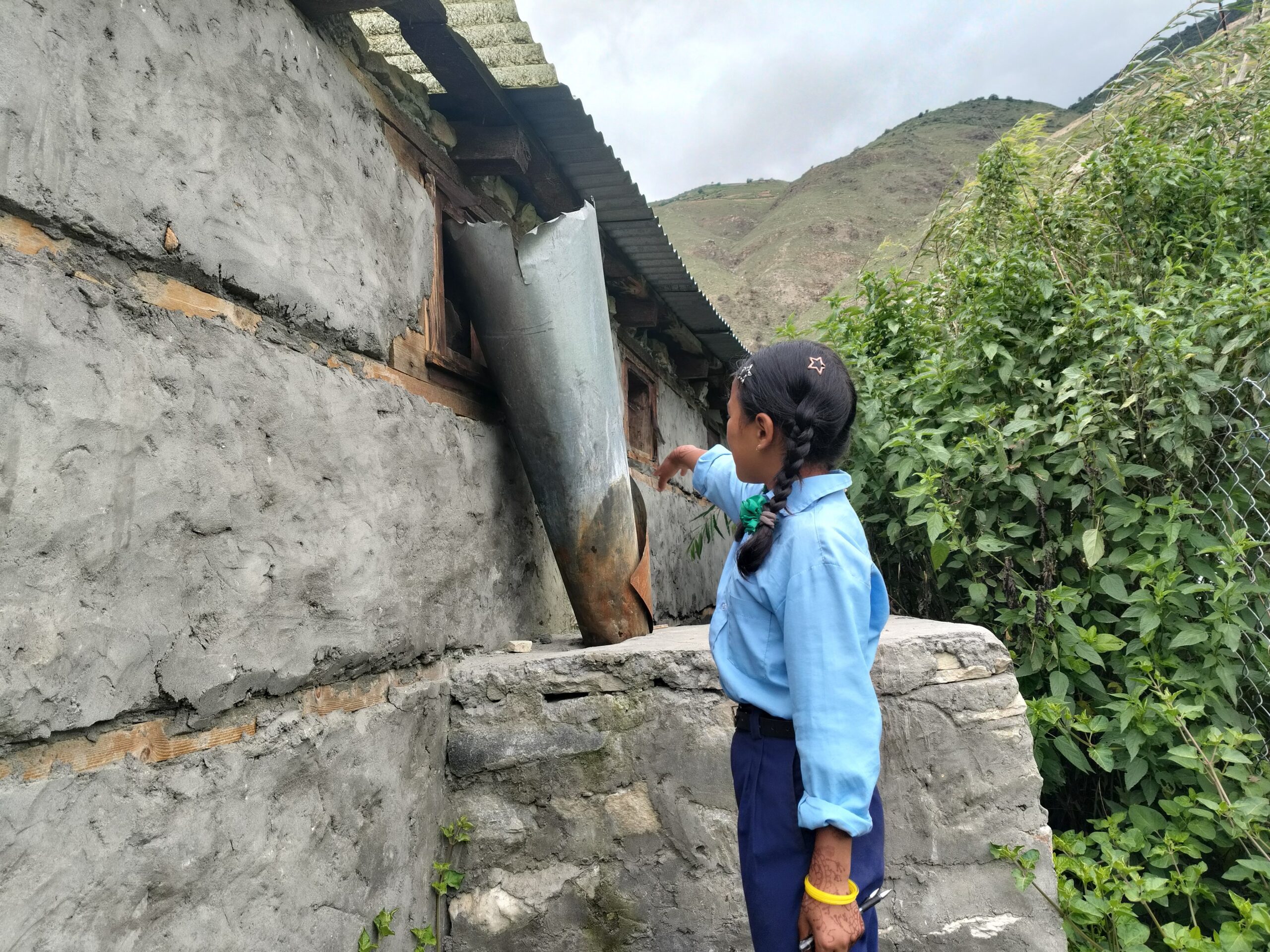 Sabitri in her school uniform pointing out to the pad disposal pit in her school. 