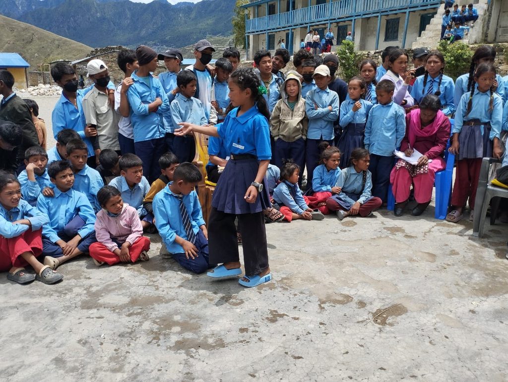 Sabitri in her school uniform with other students of school listening to her.