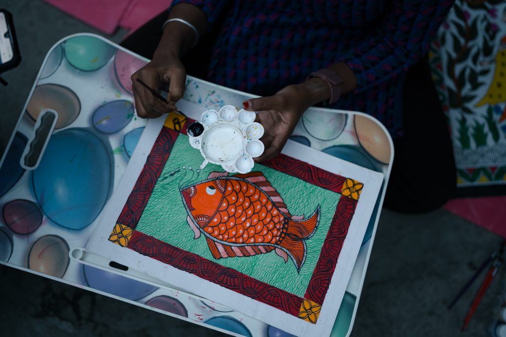 Ruhi holding paint brush and colouring fish.