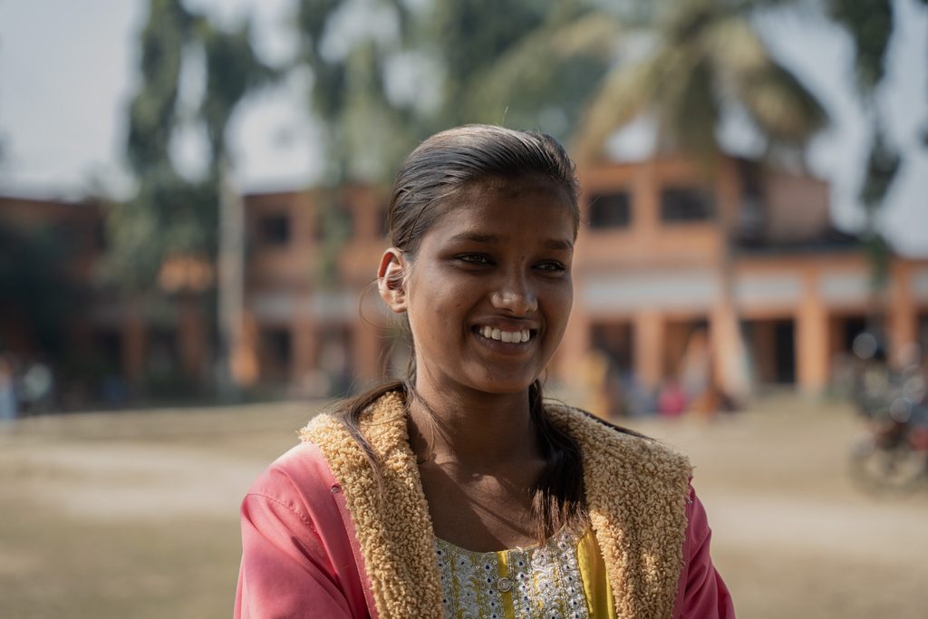 A girl wearing pink jacket and smiling.