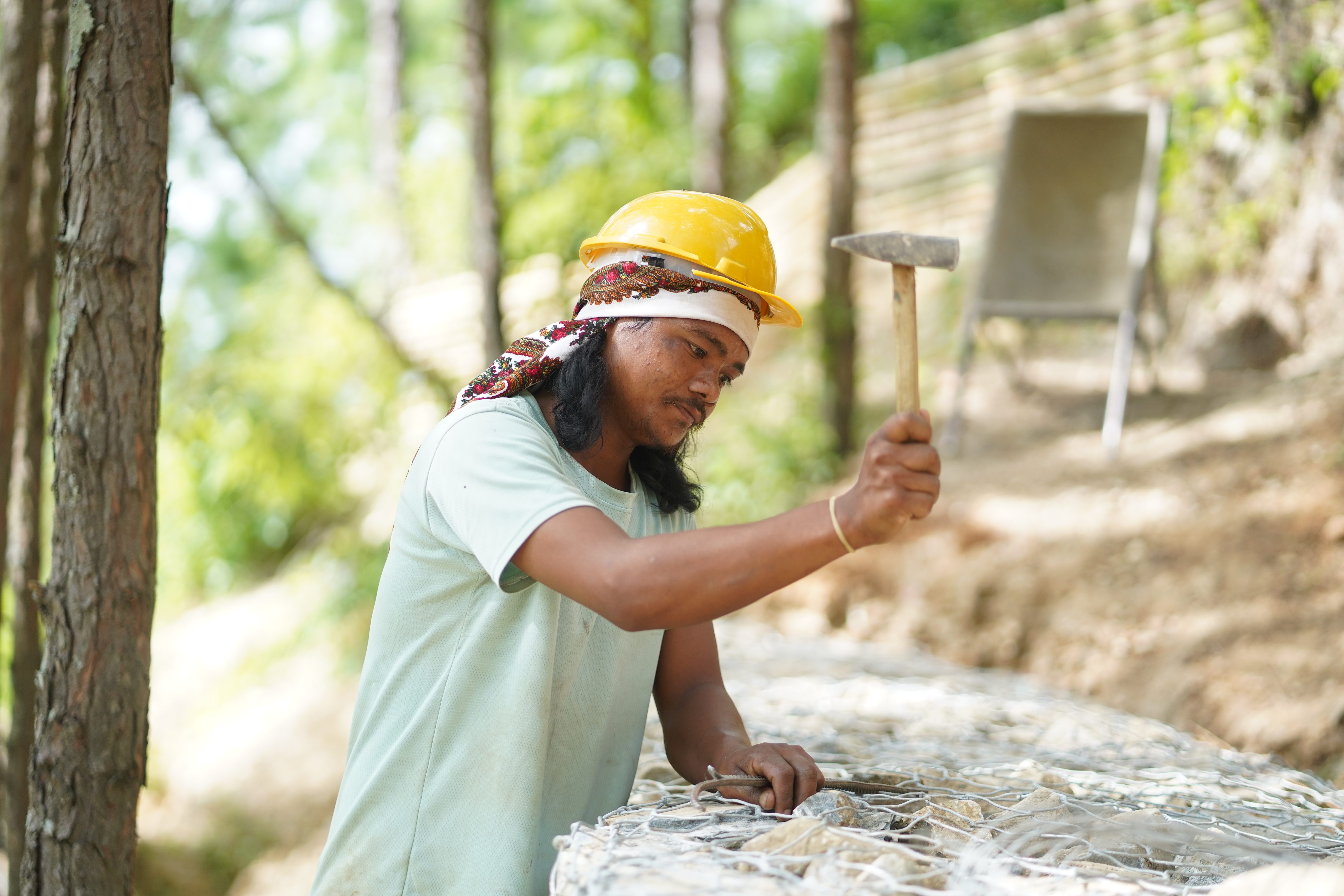 Som Lal wearing hard hat, hammer in his hand and working at construction site.