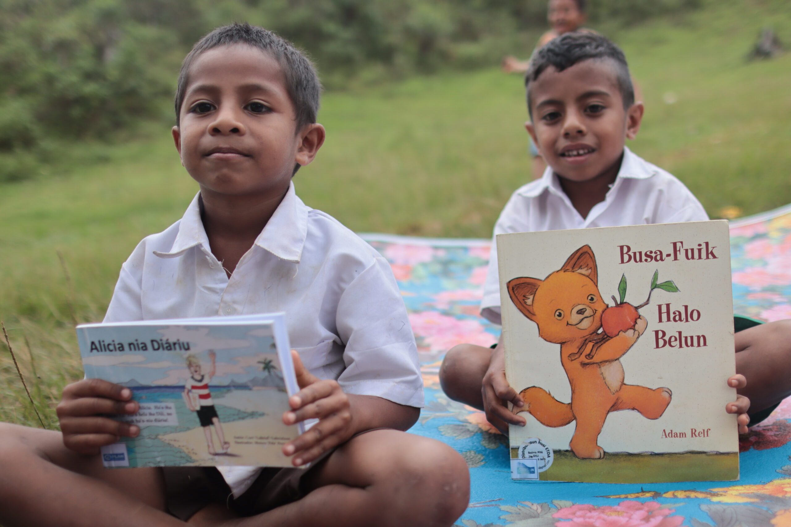 Roberu is holding the book Alicia, while his friend holds a book about wildcats.