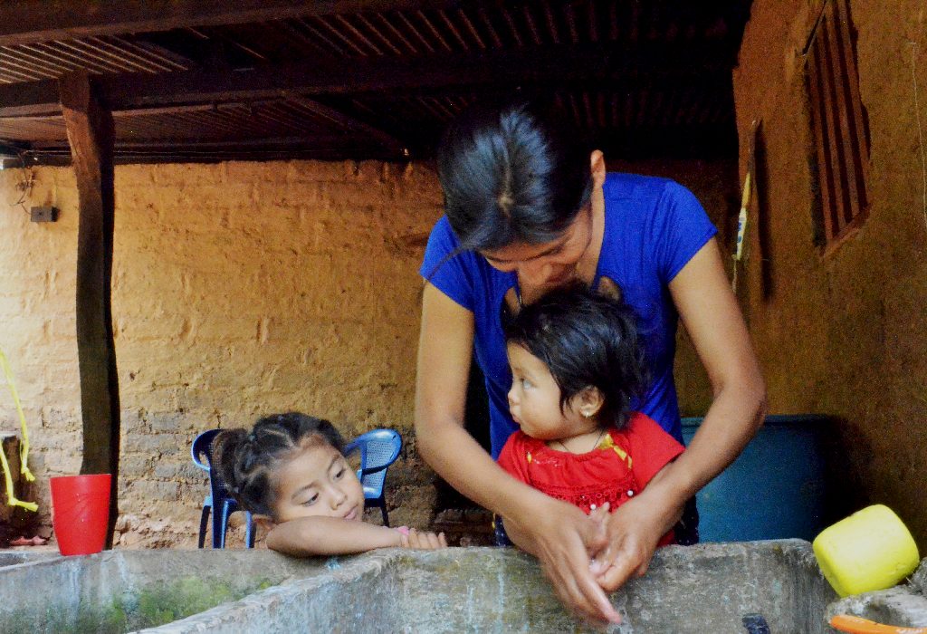 Nilsa lava las manos de sus hijas como parte de las prácticas de higiene y saneamiento.