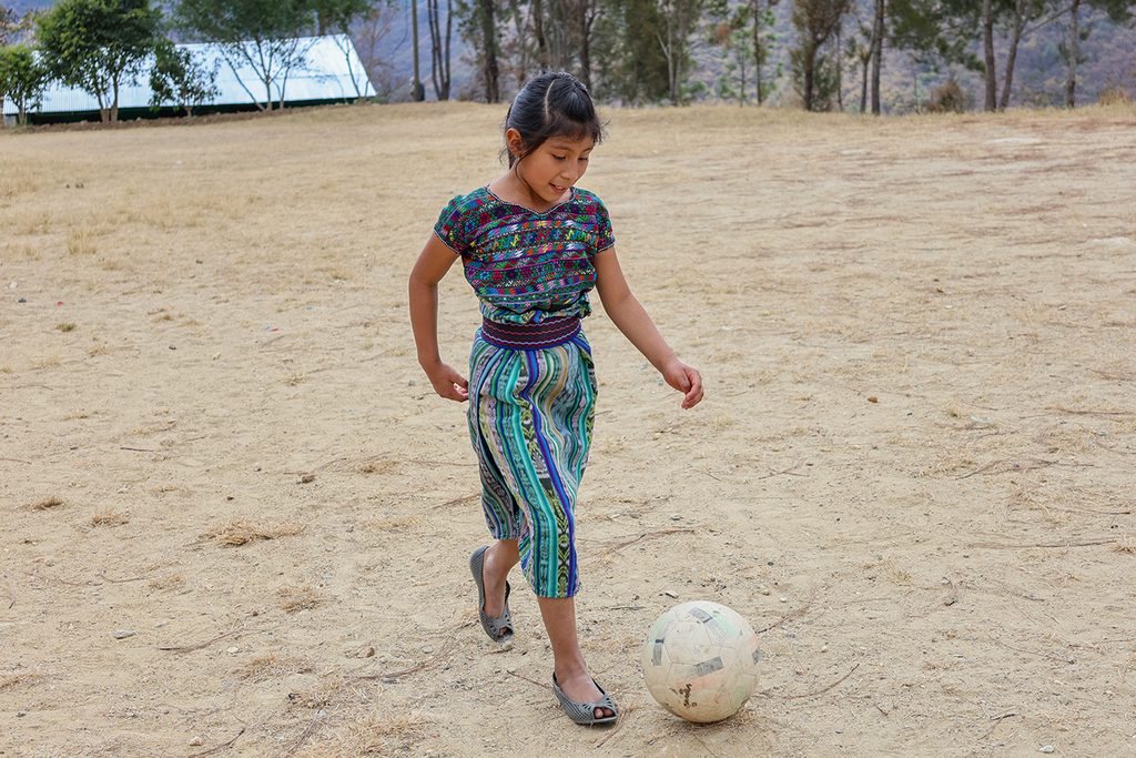 Merly, 11 años, juega fútbol en el patio de su escuela.