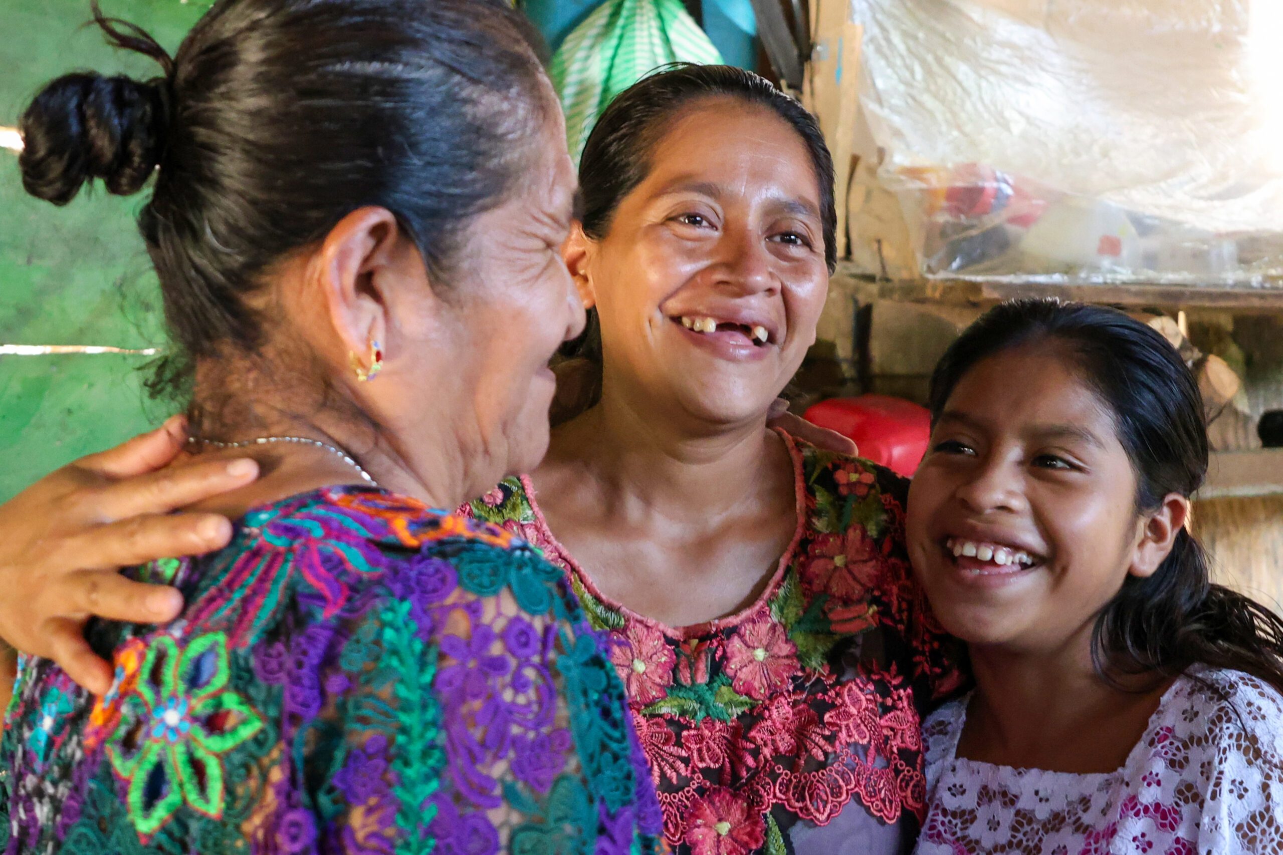 Raquel, su mamá y su abuela se abrazan en casa, mostrando unión entre generaciones.
