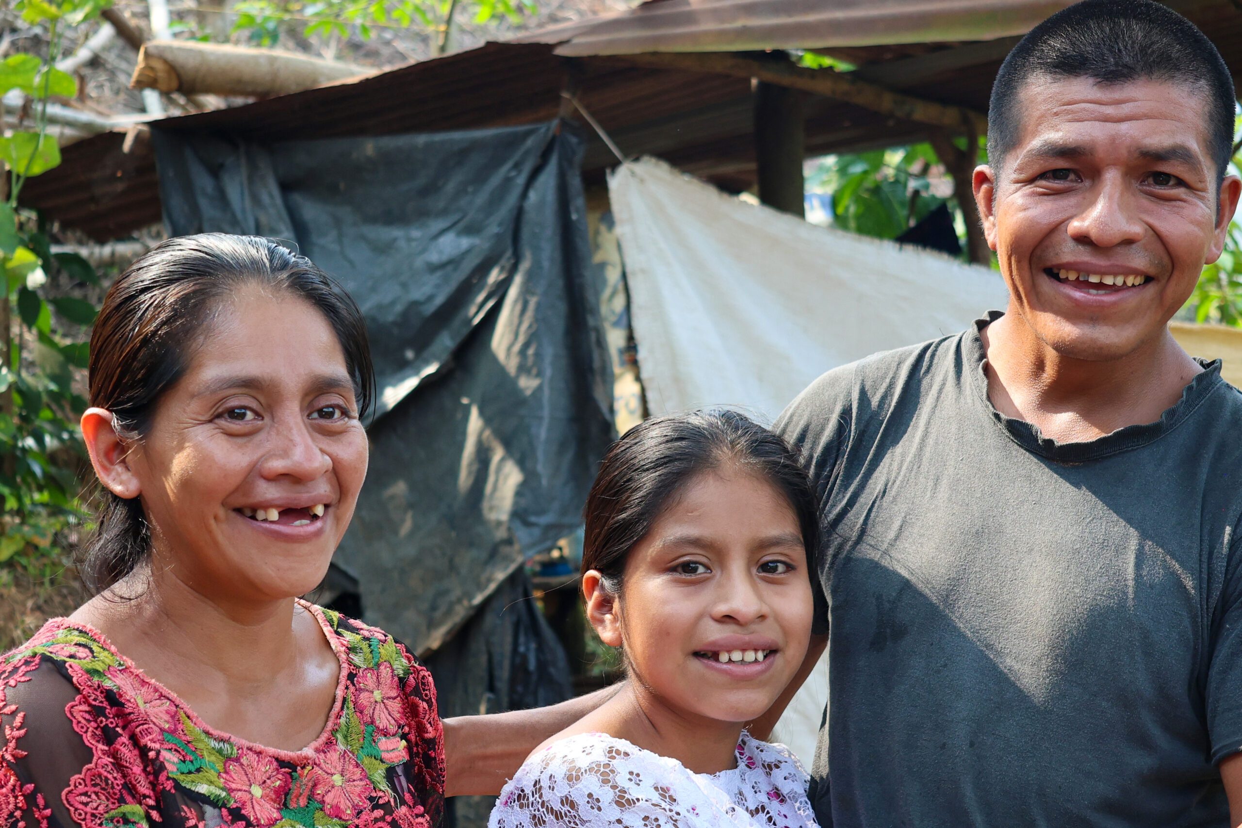 Raquel posa con su mamá y su papá, los tres de pie frente a la cámara.