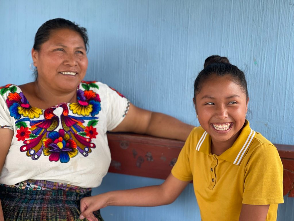 Kimberly junto a su madre, ambas sonriendo, en una comunidad rural de Guatemala.