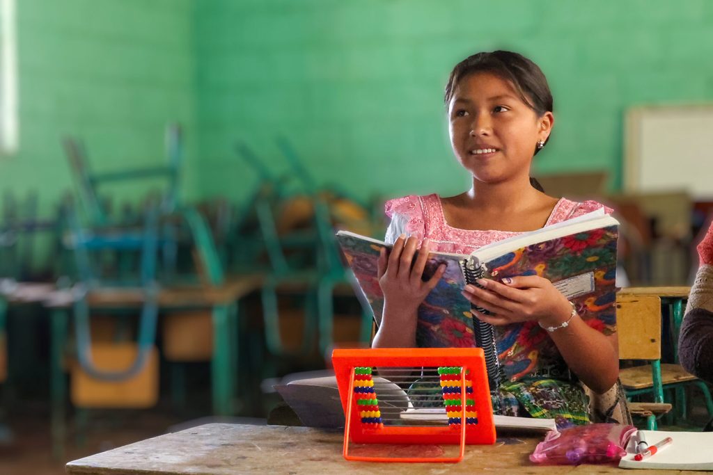 Adolescente guatemalteca en clase, leyendo un libro durante una sesión de educación extraescolar en una comunidad rural de Guatemala.