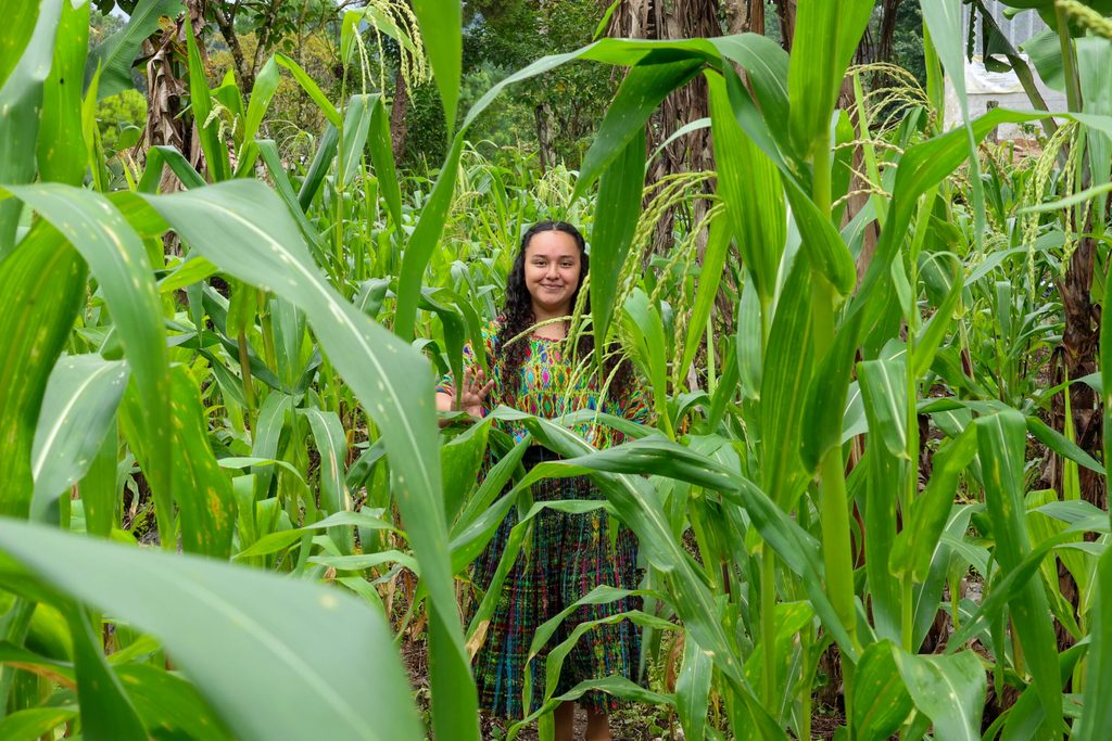 Joven lideresa posando entre milpas en su comunidad.