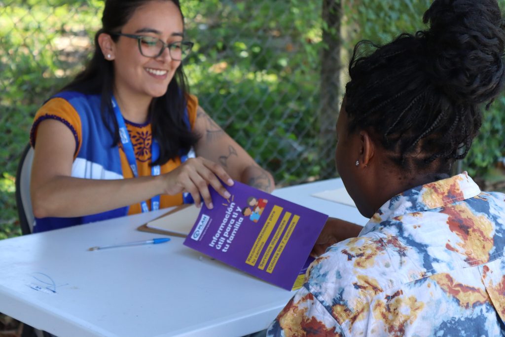 Plan International México brindando información a una mujer en movilidad.
