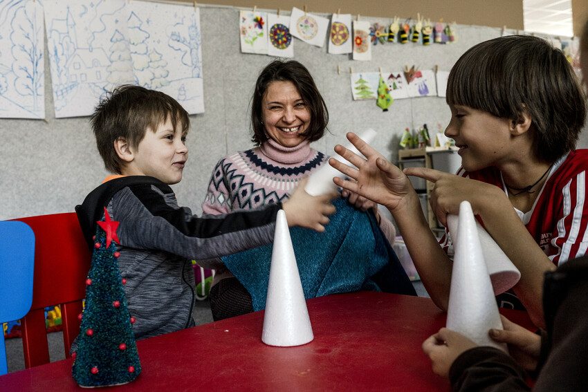 Iryna helps children make Christmas trees at the day care centre