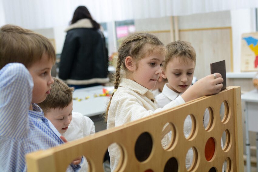 Girls and boys play with a large wooden connect 4. 