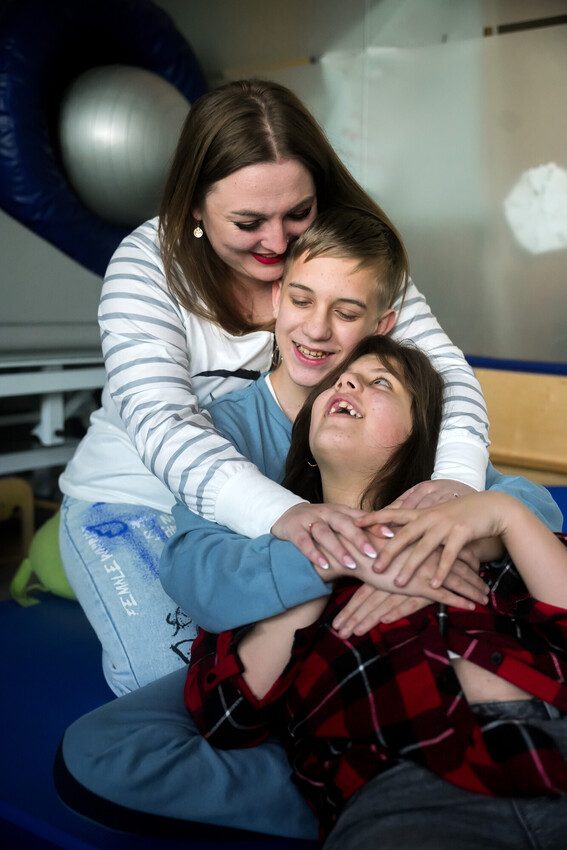 Nataliia, Alesia and her brother are hugging. 