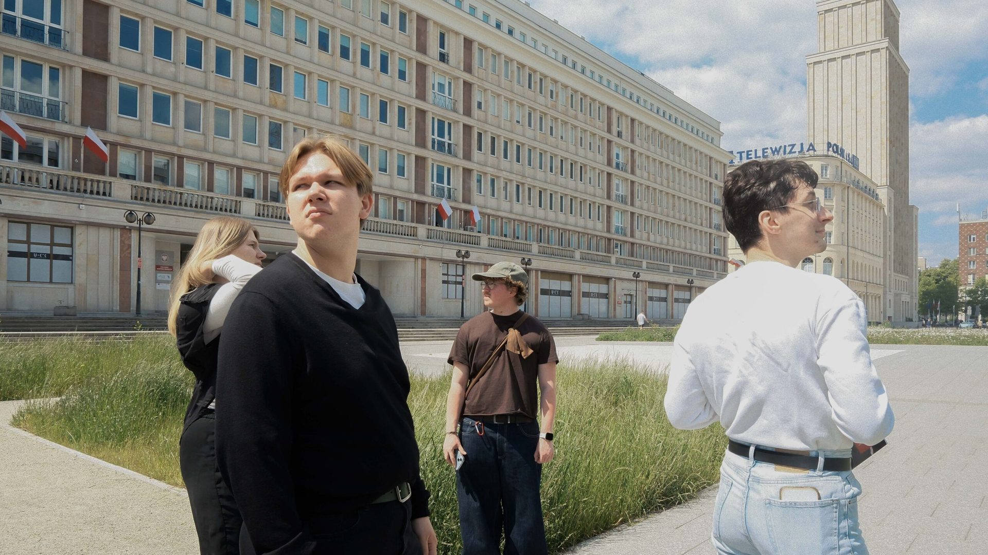Group of young people standing next to a big building.